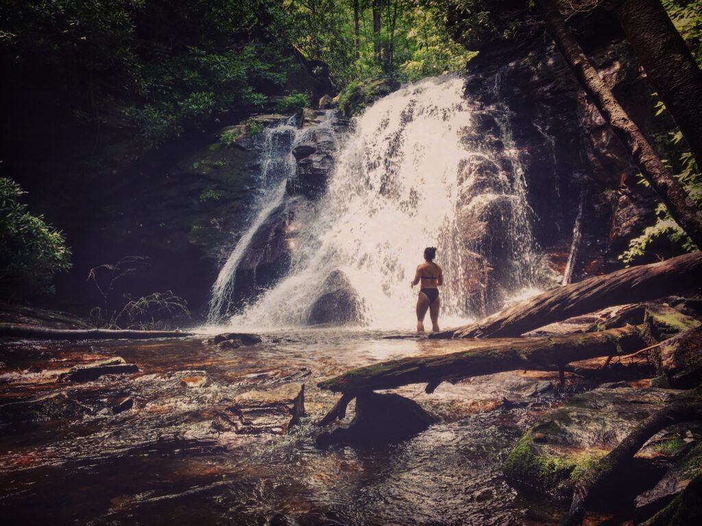 A girl standing in front of a big cascading waterfall in North Georgia.
