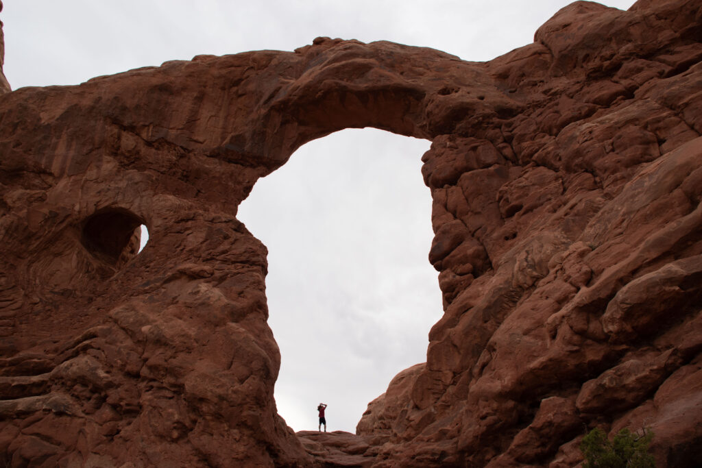 A man standing in the middle of the Arch near the entrance to the National Park Utah