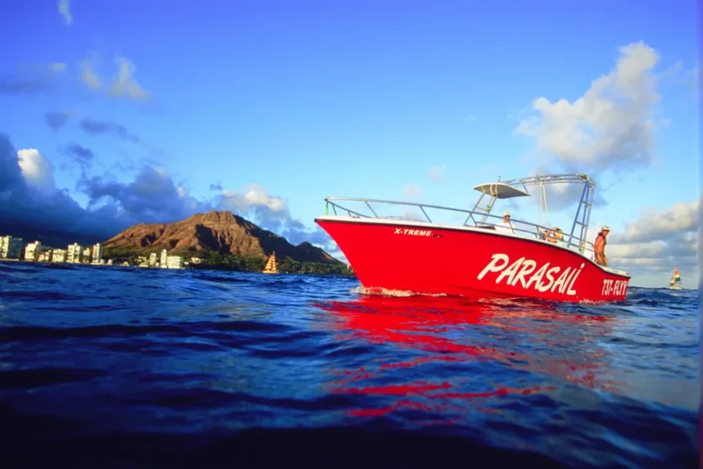 Red parasail boat with Diamond Head Volcano in the background.