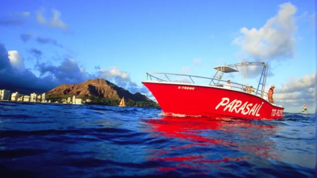 Red parasail boat with Diamond Head Volcano in the background.