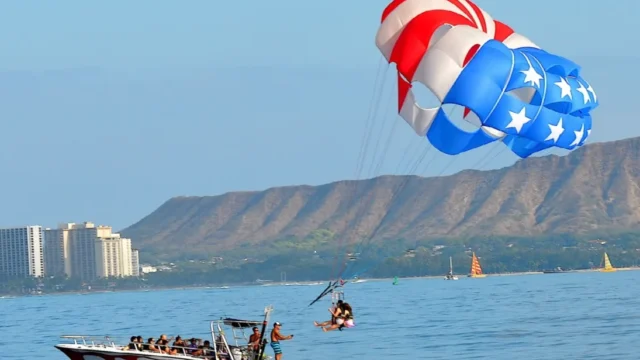 Parasailers landing back on the boat with Diamond Head Volcano in the background.