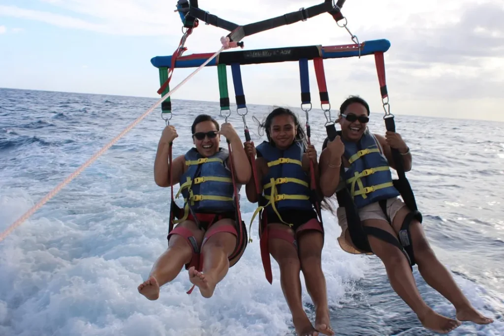 Three parasailers getting their feet dipped in the ocean.