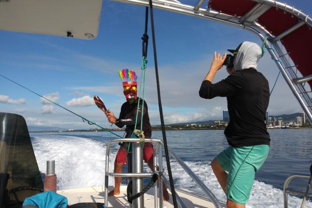 A photographer snaps a photo of a man in a tiki mask holding an axe to the parasail line in Honolulu.