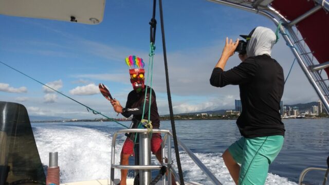 A photographer snaps a photo of a man in a tiki mask holding an axe to the parasail line in Honolulu.