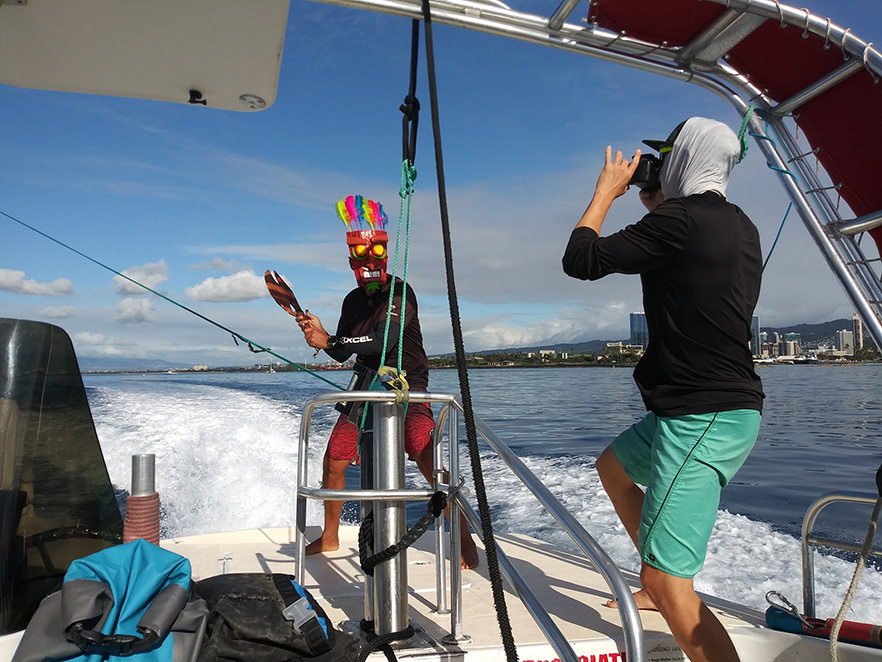 A photographer snaps a photo of a man in a tiki mask holding an axe to the parasail line in Honolulu.