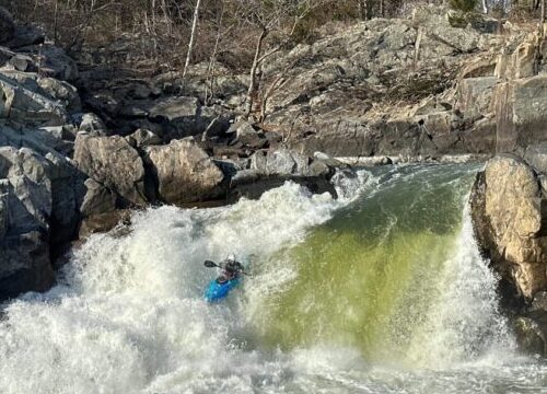 a kayaker kayaking through a rapid.