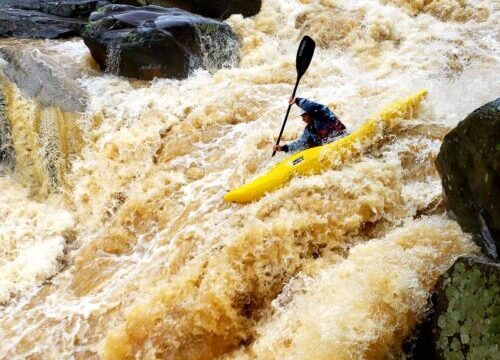 a kayaker kayaking through a rapid.