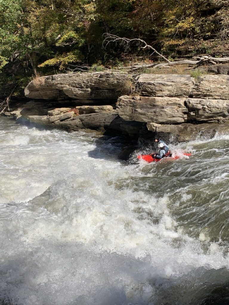 a kayaker kayaking through a rapid.