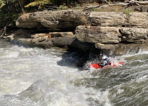 a kayaker kayaking through a rapid.