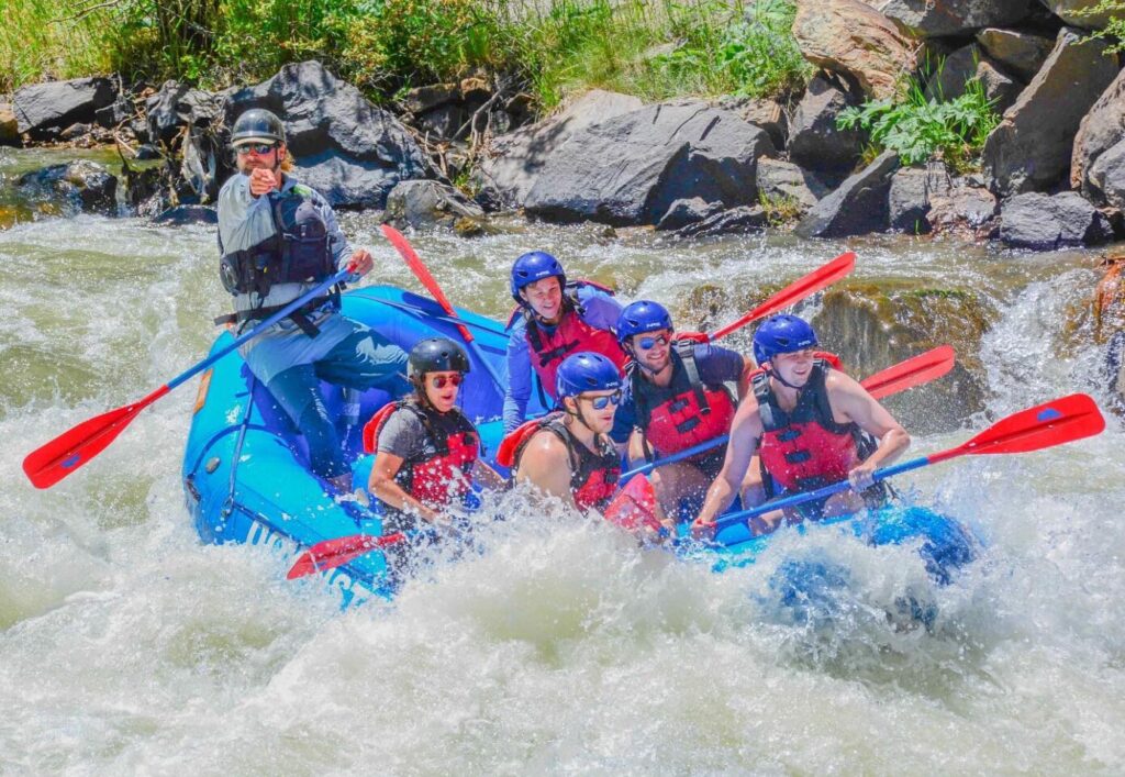 Whitewater rafters splashing into a rapid.