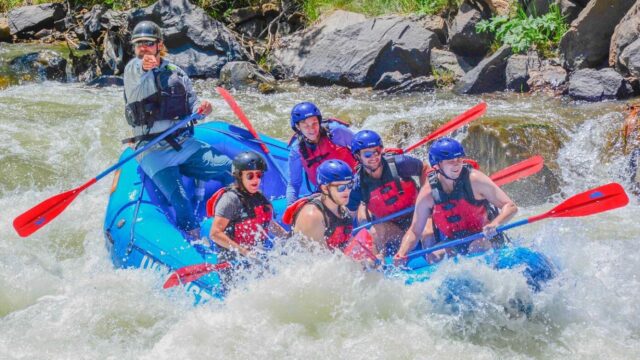 Whitewater rafters splashing into a rapid.