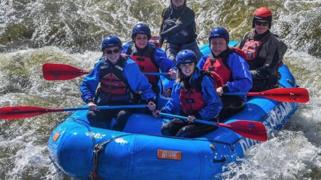 Whitewater rafters splashing into a rapid.