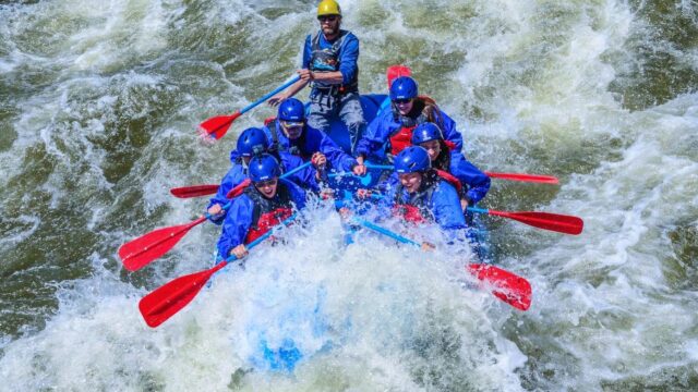 Whitewater rafters splashing into a rapid.