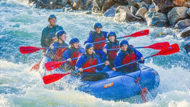 Whitewater rafters splashing into a rapid.