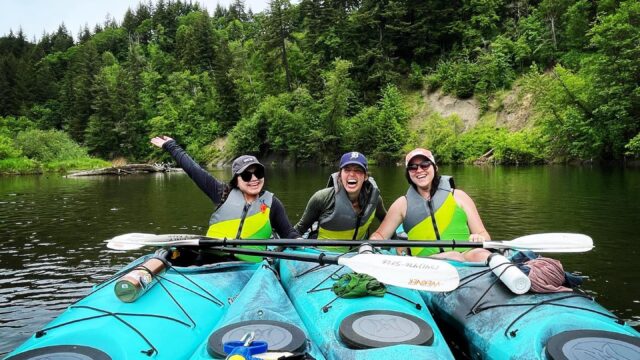 A group of kayakers on the water pose together.