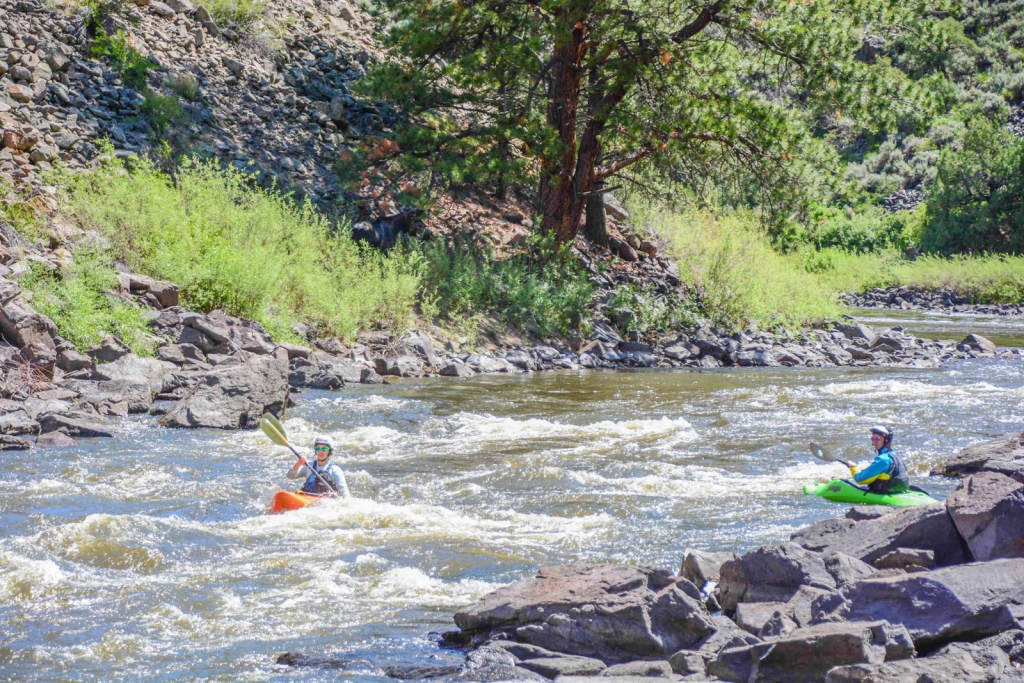 A girl Kayaking with friends on theUpper Colorado River with an orange kayak.