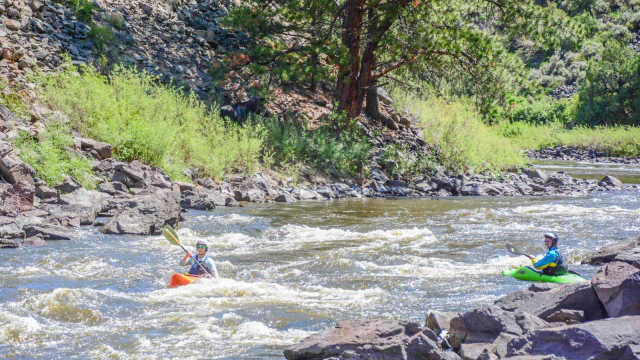 A girl Kayaking with friends on theUpper Colorado River with an orange kayak.