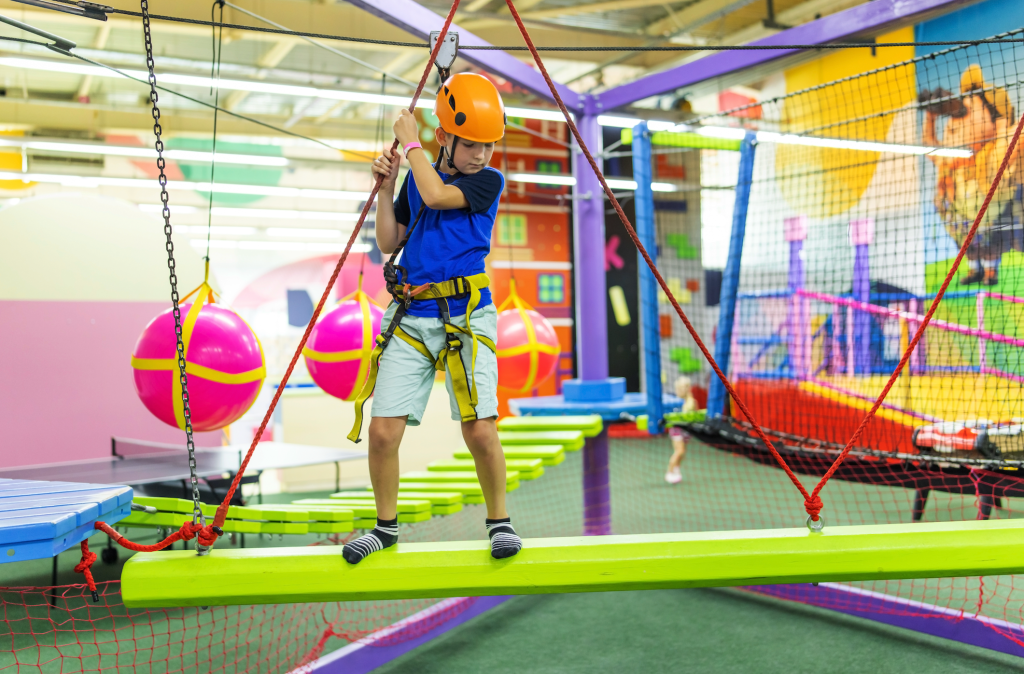 little boy on a bright indoor high ropes course.