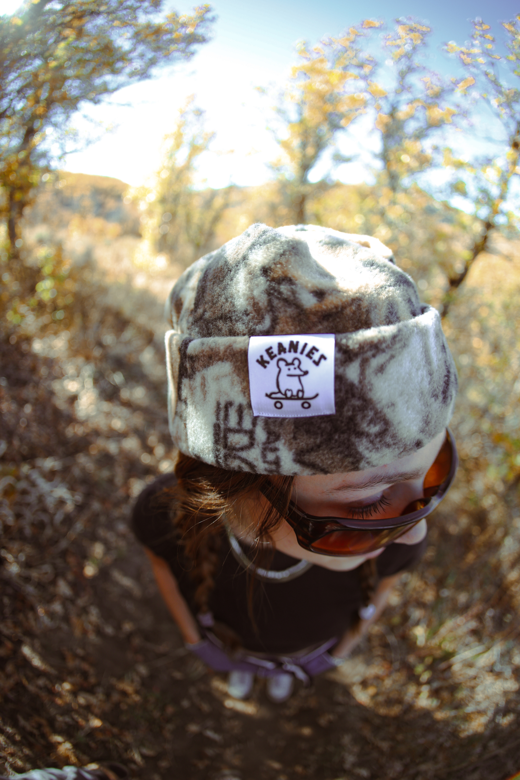 A girl standing and showing off her hat in camo.