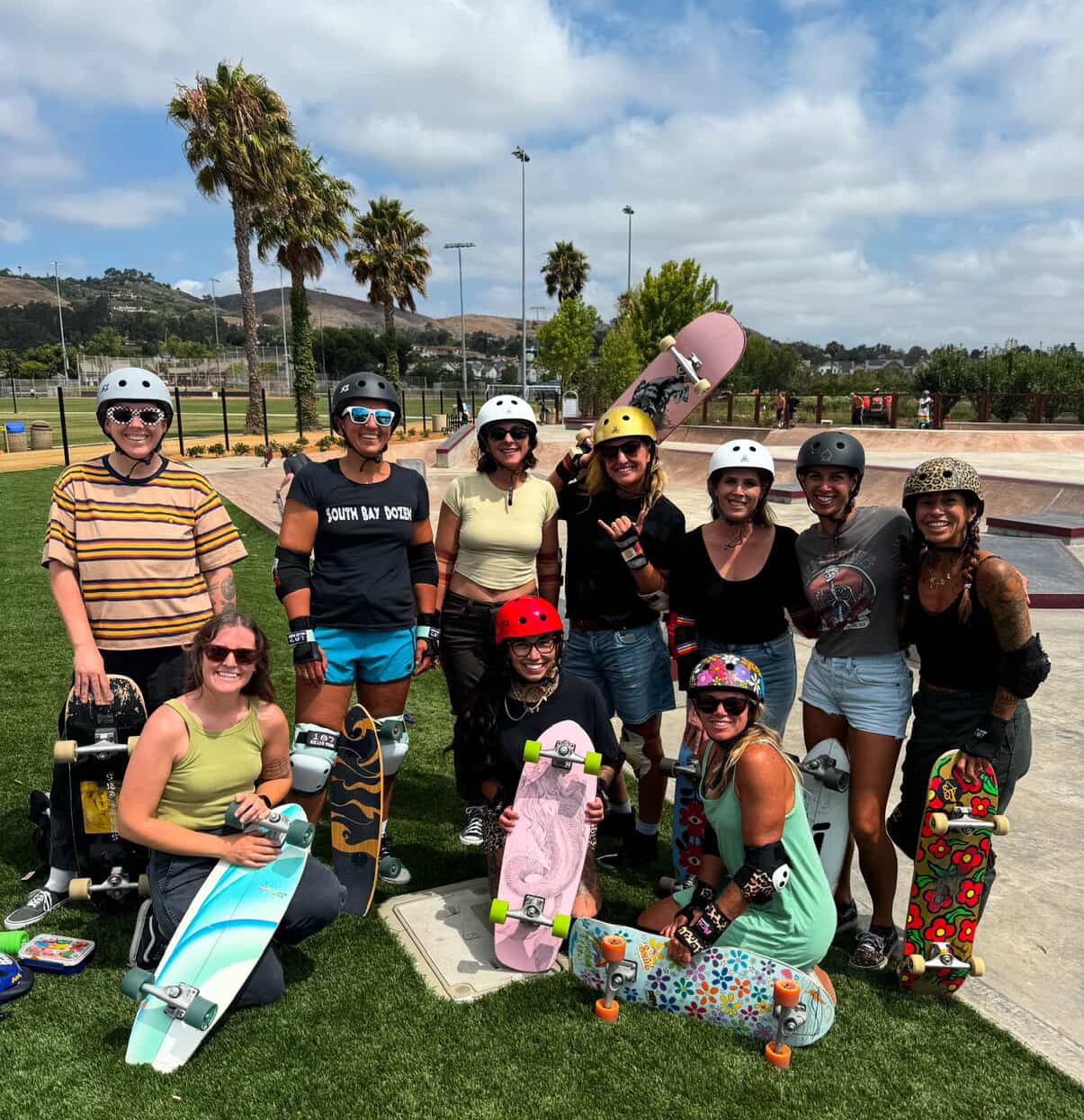 Girls together with skateboards smiling for a group photo.
