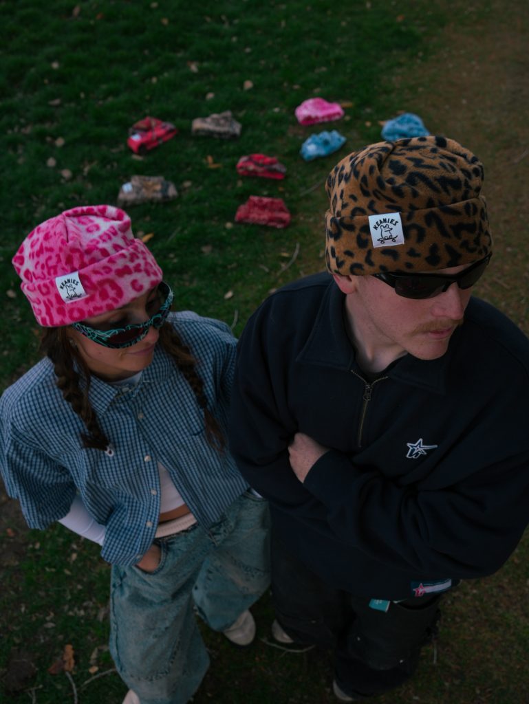 Two people standing and showing off their hats.