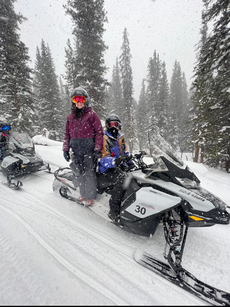 Two people snowmobiling in the snow in Colorado