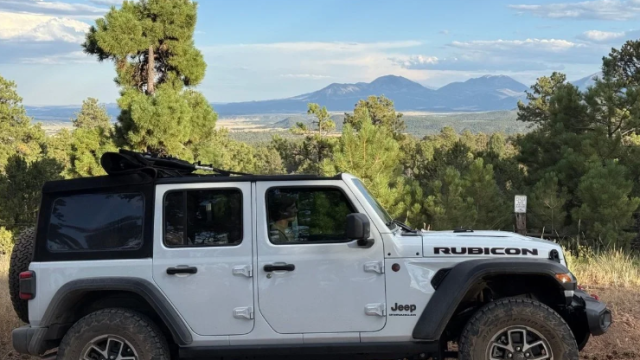 A white jeep with parked in the mountains.