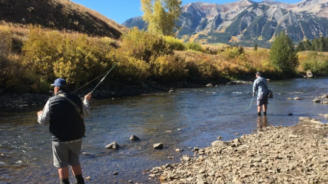 two men fly fishing with mountains in the backgorund.