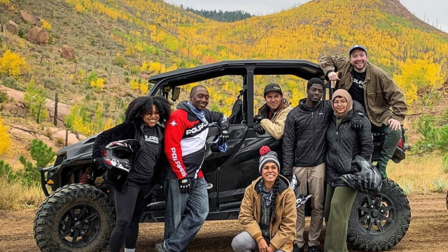 A group of people on a UTV vehicle in front of mountains.