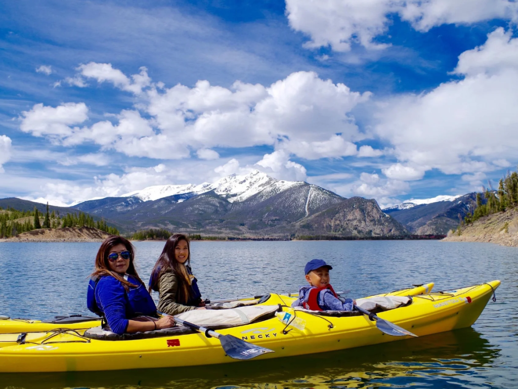 A family kayaking on a lake in the mountains.