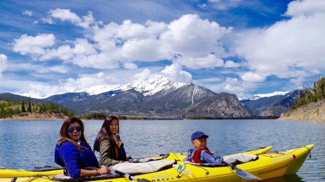 A family kayaking on a lake in the mountains.