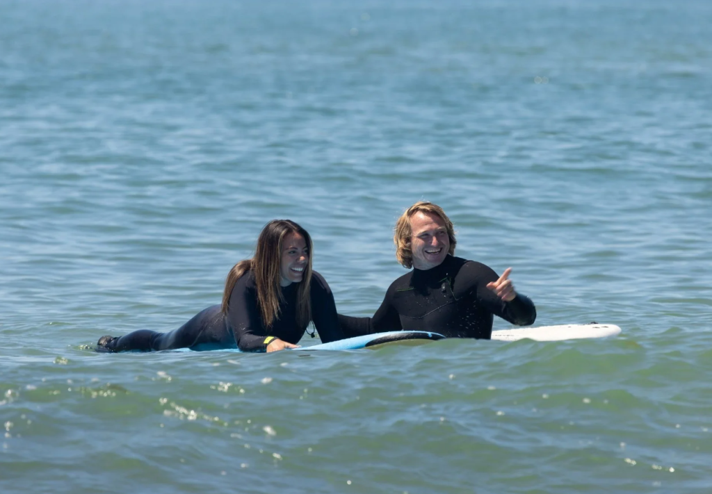A man teaching a woman to surf.