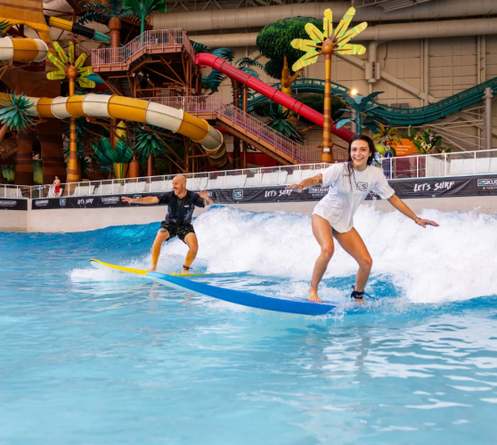 Two surfers on an indoor surf wave in New Jersey.